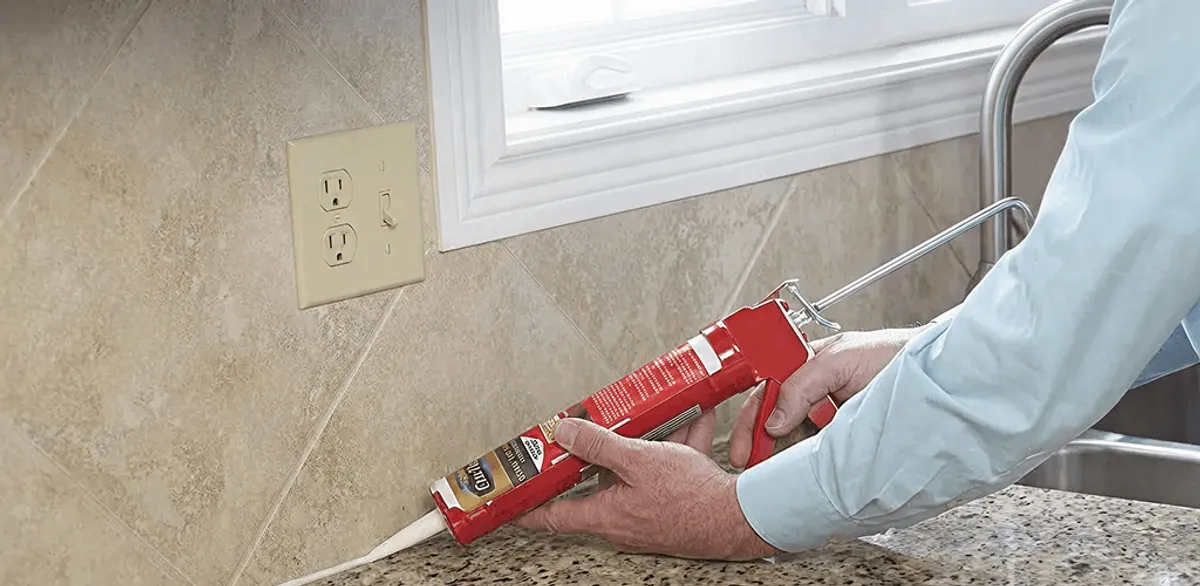 Handyman applying caulk along a kitchen backsplash and countertop seam in Tacoma, WA